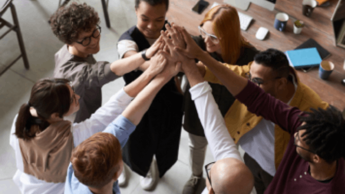 Photographie de collaborateurs tendant et joignant leurs mains en cercle.